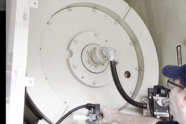 Technician working on a hydraulic drum assembly with monitoring components attached.